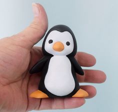 a hand holding a small penguin toy in it's palm