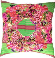 a green and pink pillow with an embroidered design on the front, along with a striped background