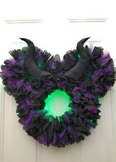 a purple and black wreath with horns on it's side hanging from a door