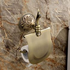 a gold toilet paper dispenser on a marble wall with an ornate design