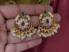 Gorgeous gold plated Ankat stone Chaandabali earrings. Statement South Indian Style Ankat Earrings. These beautiful earrings come with red and green CZ stones, White Ankat stones and pearl hangings. A gorgeous choice for any simple traditional outfit. Design 2 Item size: 2.8 cm diameter Closure: Design 1: Pushback Design 2 : screwback Ready to ship from FL USA Care: We don't want your special moments to fade. To maintain the quality of your jewelry, please => It is recommended to keep all your j Red Stone Earrings Gold Indian, Traditional Earrings Gold, Jumka Earrings, Red Stone Earrings, South Indian Style, Gold Earrings Indian, Gold Bridal Necklace, Gold Earrings Models, Traditional Outfit