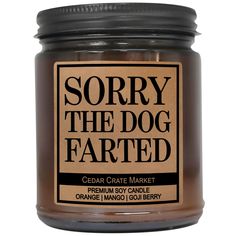 a candle that says sorry the dog farted in black and brown lettering on it