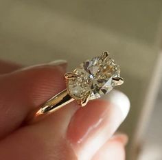 a close up of a person's hand holding a ring with a diamond in it