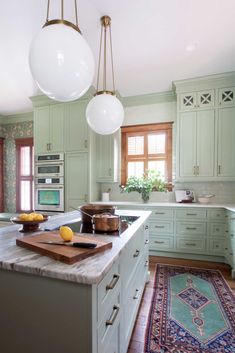 a large kitchen with green cabinets and marble counter tops, along with an area rug on the floor