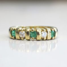 This stunning 18K yellow gold ring features two very white round brilliant cut diamonds and three bright green round emeralds. This ring is perfect for an anniversary band, wedding band, or stackable ring. The contrast of the colors makes sure this ring stands out! Metal: 18K Yellow Gold Diamonds: .20 CTW, VS1-VS2, E-F Color Emeralds: 3 MM Each Band Width: 3.44 - 5.00 MM Size: 7 For a greater selection of jewelry please visit our website at www.BlackMarketLLC.com If you have any questions about Classic Green Emerald Ring With Single Cut Diamonds, Green Emerald Ring With Single Cut Diamonds For Promise, Emerald Green Promise Ring With Single Cut Diamonds, Classic Green Rings With Single Cut Diamonds, Classic Green Diamond Ring With Single Cut Diamonds, Green Diamond Ring With Single Cut Diamonds For Anniversary, Green Emerald Ring With Single Cut Diamonds, Green Round Diamond Ring With Channel Set, Classic Green Channel Set Emerald Ring