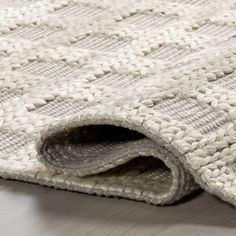 a close up view of a rug on the floor with white and gray squares in it