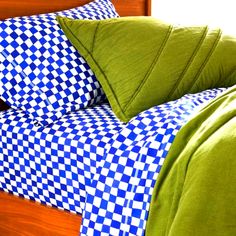 a bed with blue and white checkered sheets, pillows and pillow cases on it