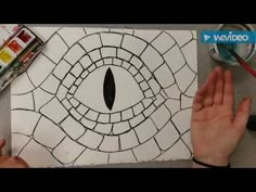 someone is drawing an eye in the middle of a piece of paper with their hands