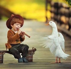 a young boy sitting on a bench next to a white duck and holding a flute