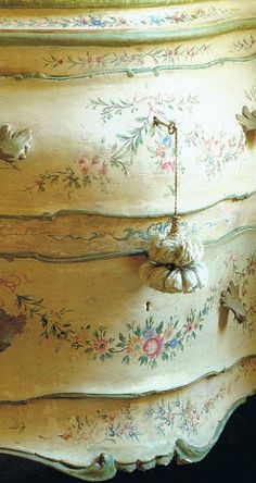 an old dresser painted yellow with flowers and leaves on it's sides, sitting against a black background