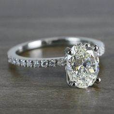 an oval cut diamond engagement ring with pave set diamonds on the band and side stones