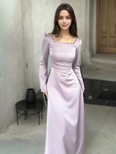 a woman in a long purple dress posing for the camera