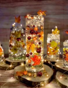 there are many glass vases with autumn decorations in them