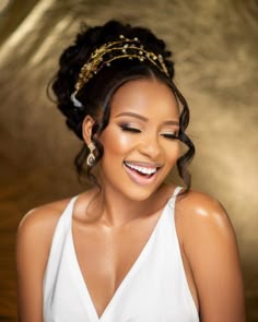 a smiling woman wearing a white dress and gold headpiece