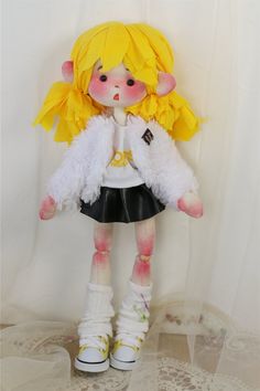 a doll with blonde hair wearing a white jacket and black skirt is standing in front of a curtain