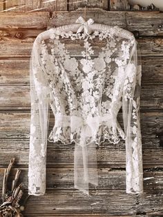 a white lace top hanging on a wooden wall