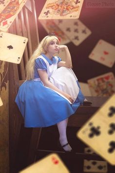 a woman sitting on top of a wooden chair surrounded by playing cards