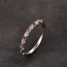 a gold ring with purple and blue stones on the inside, sitting on a black surface