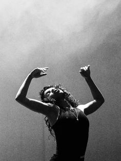 a black and white photo of a woman with her arms up in the air,