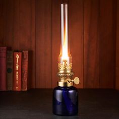 a blue glass lamp with a gold crown on it's head sitting next to some books