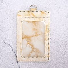 a white and tan leather tag hanging on a wall with a hole in the middle