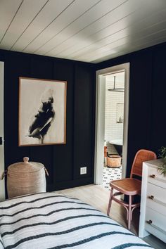 a bedroom with black walls and white bedding has a painting hanging on the wall