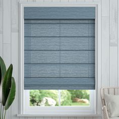 a blue roman blind in a white room with a chair and potted plant on the window sill