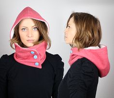 two women with hoods on their heads, one wearing a black top and the other pink