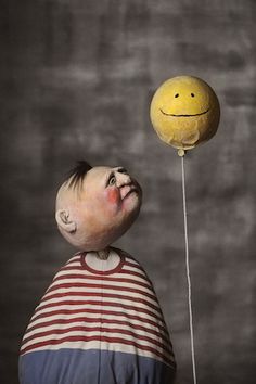 a child is holding a balloon with a smiley face on it and the caption says,