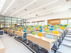 an empty classroom with rows of desks and chairs in front of large windows on the wall