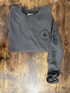 a gray sweatshirt with the words emergency on it sitting on top of a wooden floor