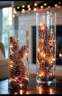 two glass vases filled with pine cones on top of a table