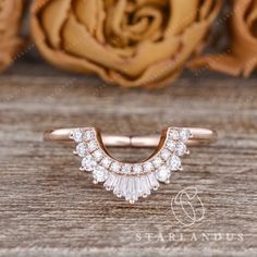 a rose gold ring with white diamonds on it and a rose in the back ground