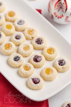 small cookies on a white plate with powdered sugar and jelly in the shape of hearts