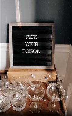 there is a sign that says pick your poson on the table with many glasses