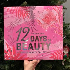 a person holding up a pink box with the words 12 days of beauty on it