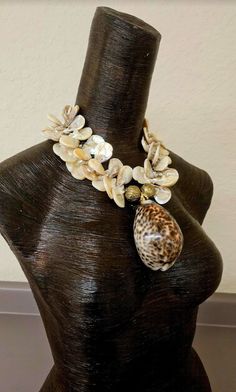 a brown mannequin with seashells and shells on it's neck