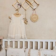 a white crib with pillows and stuffed animals hanging on the wall next to it