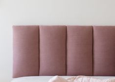 the headboard of a bed with pink sheets and pillows