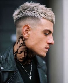 a man with a shaved head and tattoos on his neck, wearing a black leather jacket