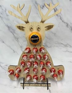 a wooden reindeer with chocolate candies in it's mouth on a marble surface