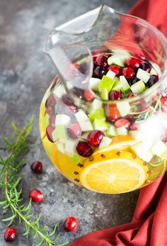 a pitcher filled with fruit and vegetables on top of a table