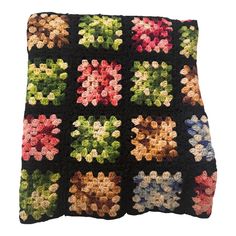 a black crocheted pillow with multicolored flowers on it