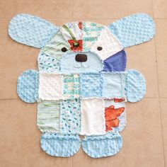 a teddy bear made out of baby's quilts on the floor with its eyes closed