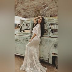 a woman standing next to an old car wearing a dress with sequins on it