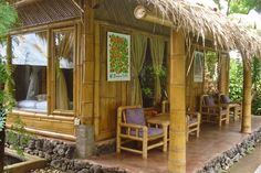 a bamboo hut with chairs and tables on the outside patio area, surrounded by greenery