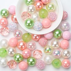 a white bowl filled with lots of different colored balls and pearls on top of a table