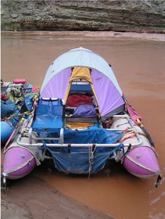 an inflatable raft sitting on top of muddy water next to a shore line