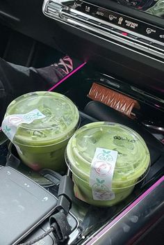 two cups of green tea sitting in the center console of a car