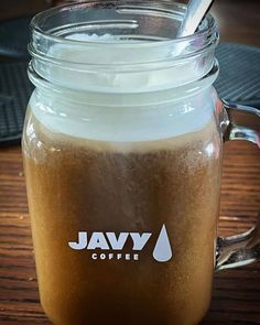 a glass jar filled with liquid sitting on top of a wooden table next to a spoon